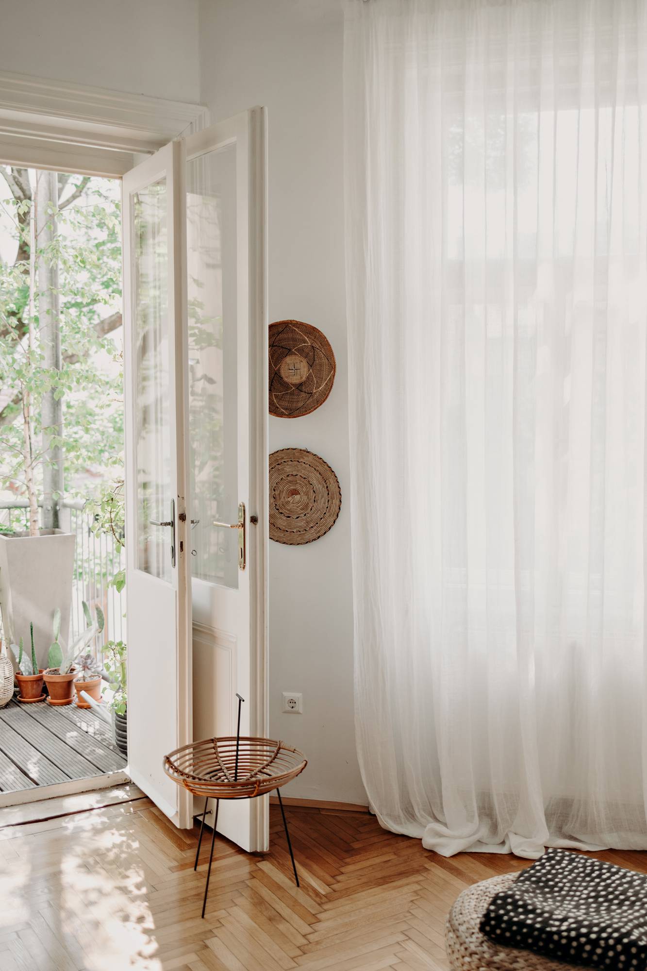 offenes Wohnzimmer mit begrüntem Balkon und Leinenvorhängen